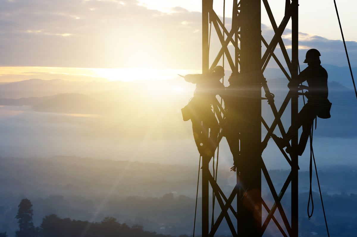 Silhouette of a technician working at a height against the sky